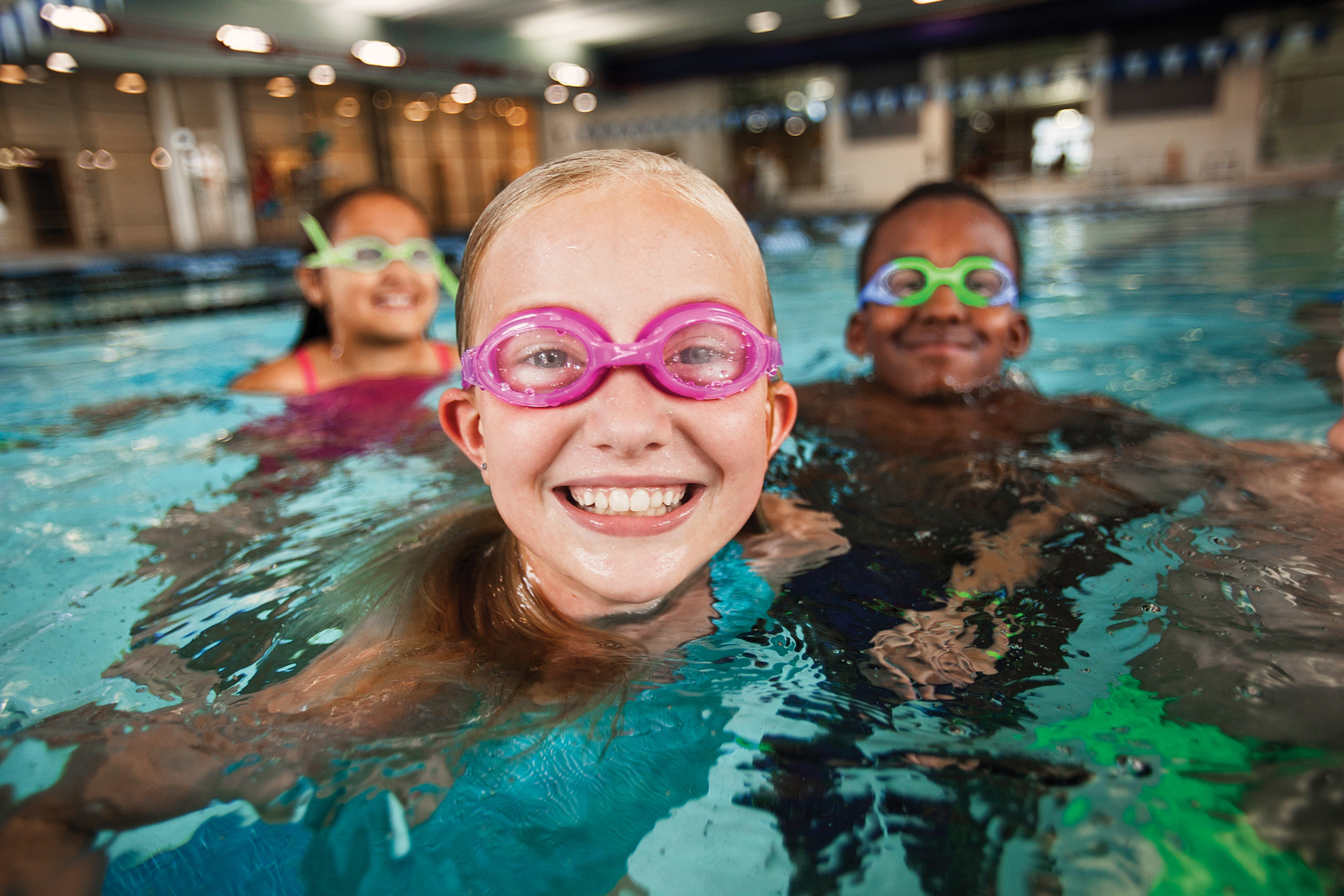 Young children smiling while swimming with goggles on.