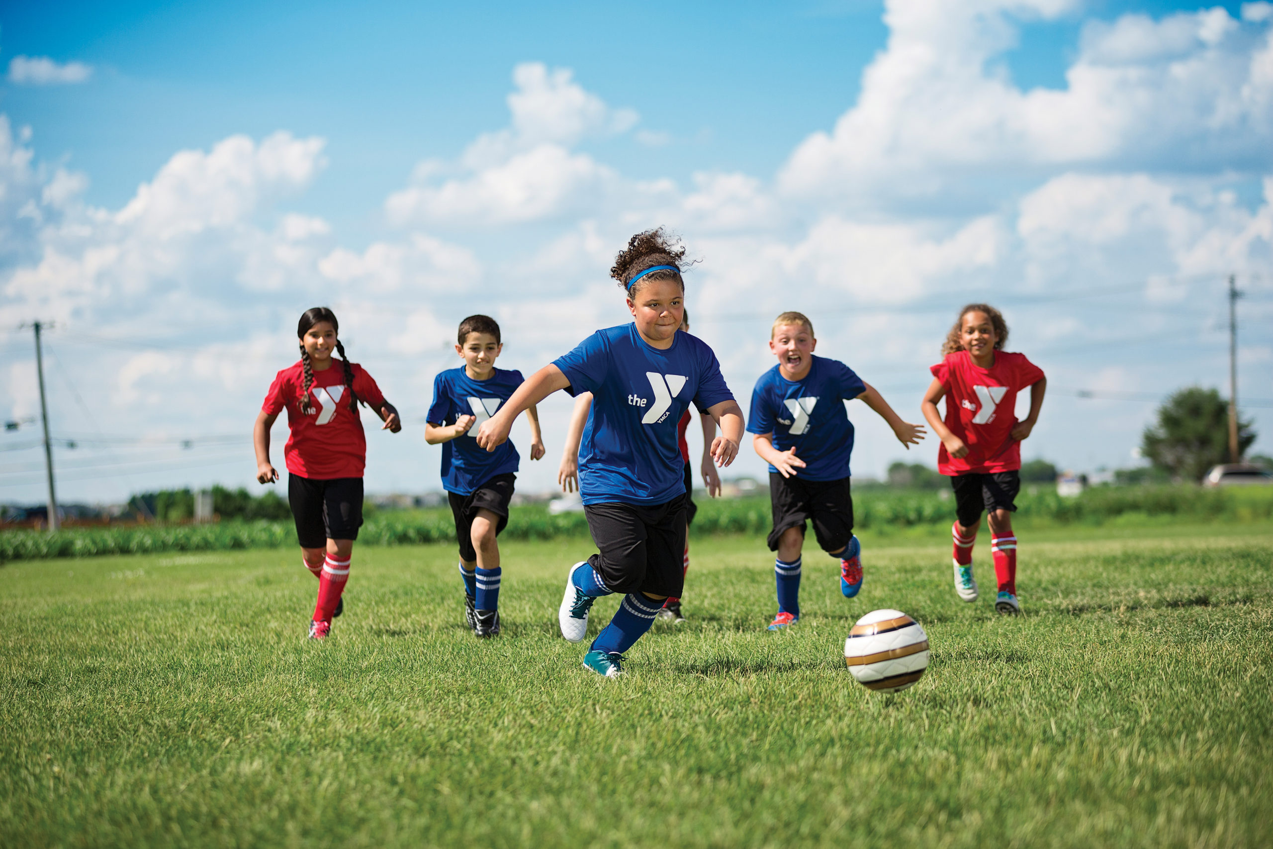 Kids playing soccer running after the ball.