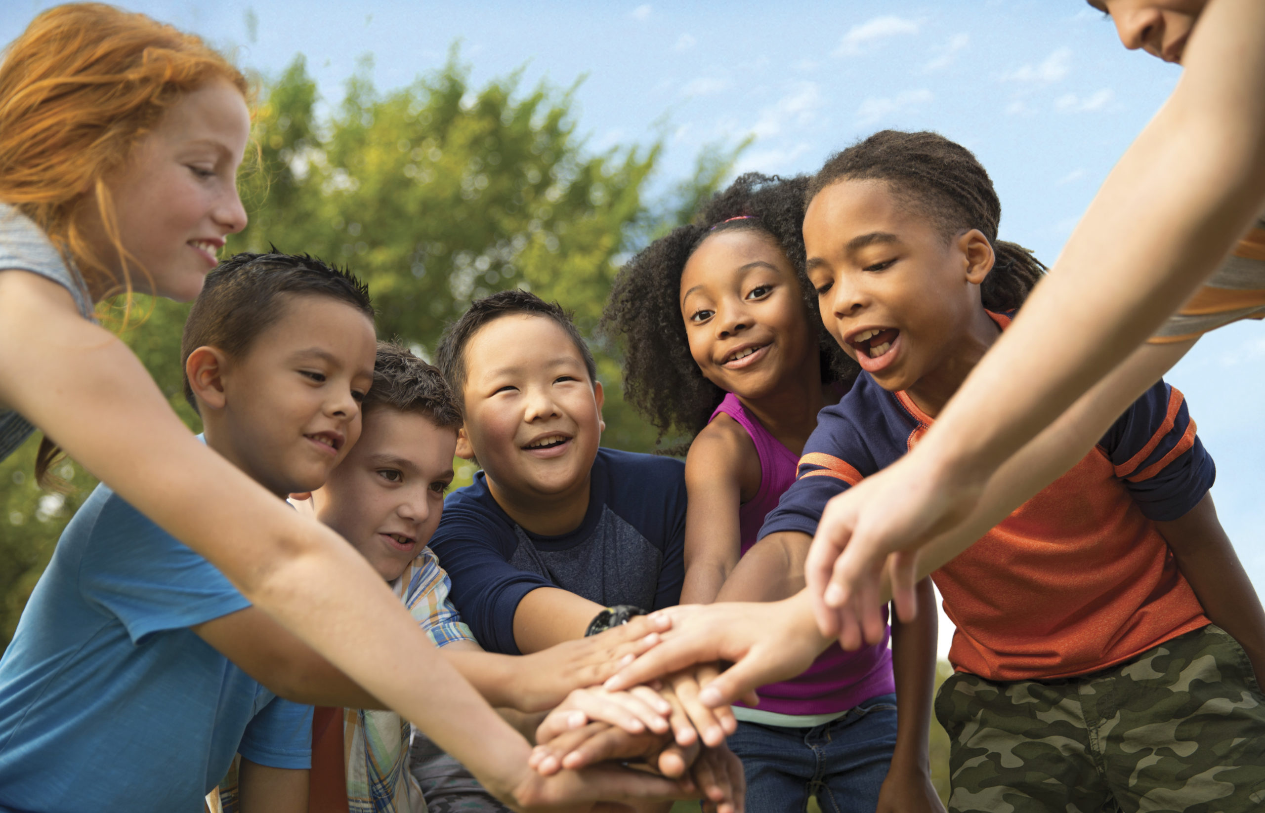 Kids in a group putting their hands together as a team.