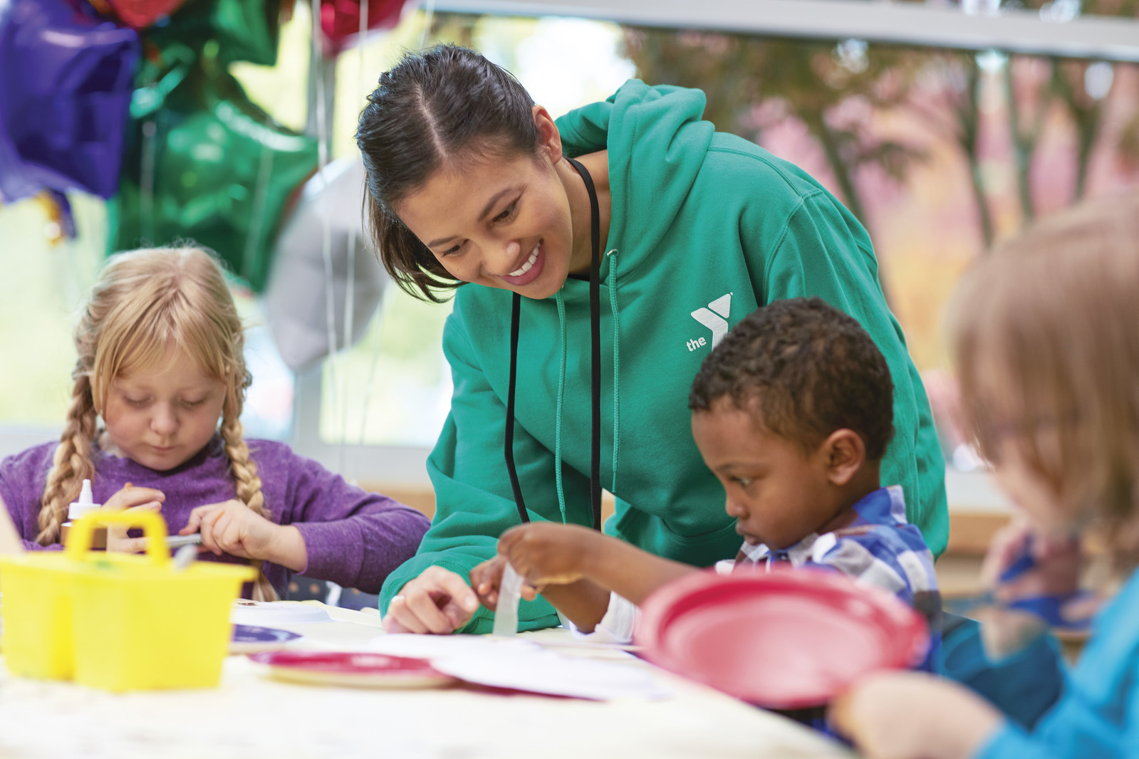 YMCA staff helping kids with an art project.