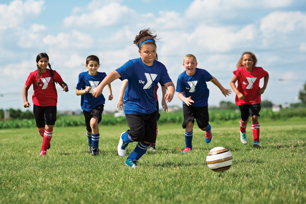 Kids playing soccer running after the ball.