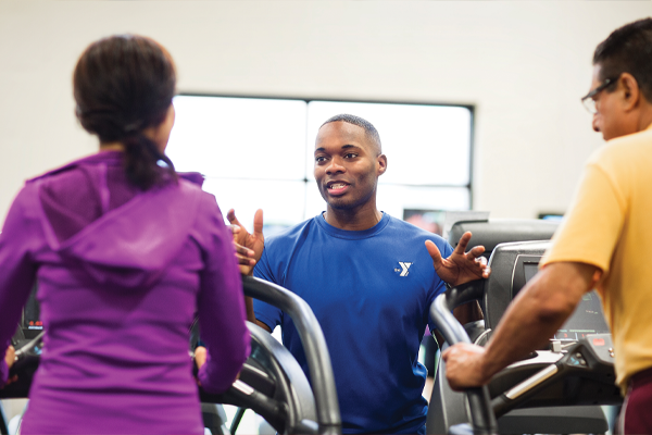 YMCA members talking to each other while on the treadmill.