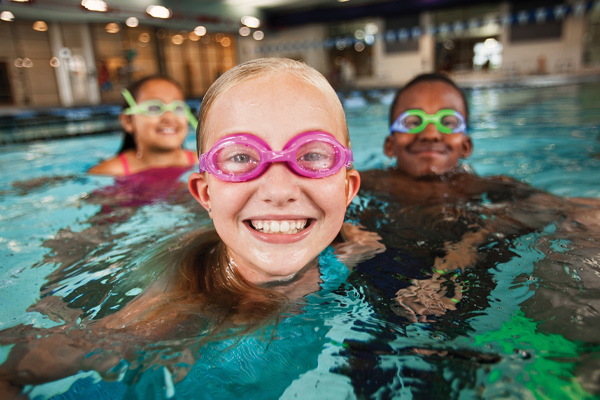 Young children smiling while swimming with goggles on.