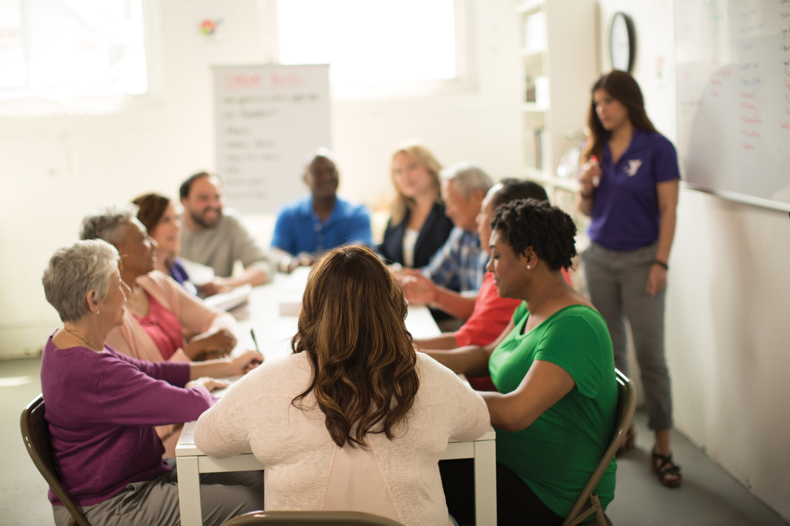 Group of adults with YMCA staff member discussing things.