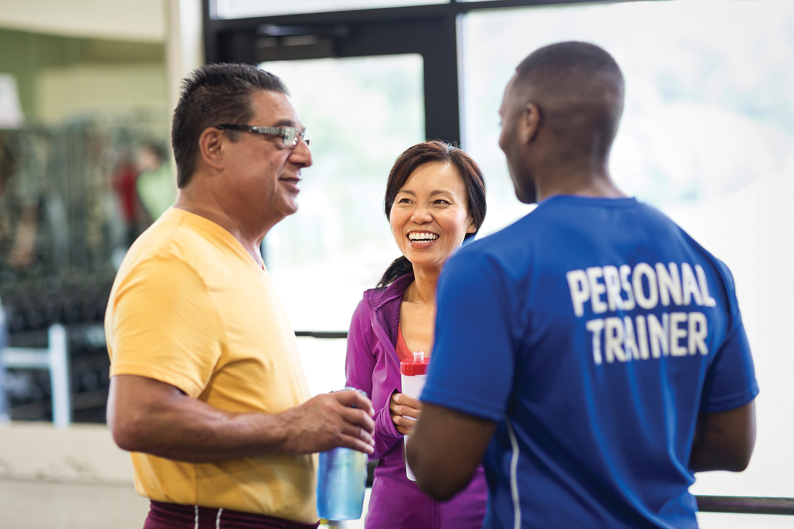 Male personal trainer speaking with two potential clients