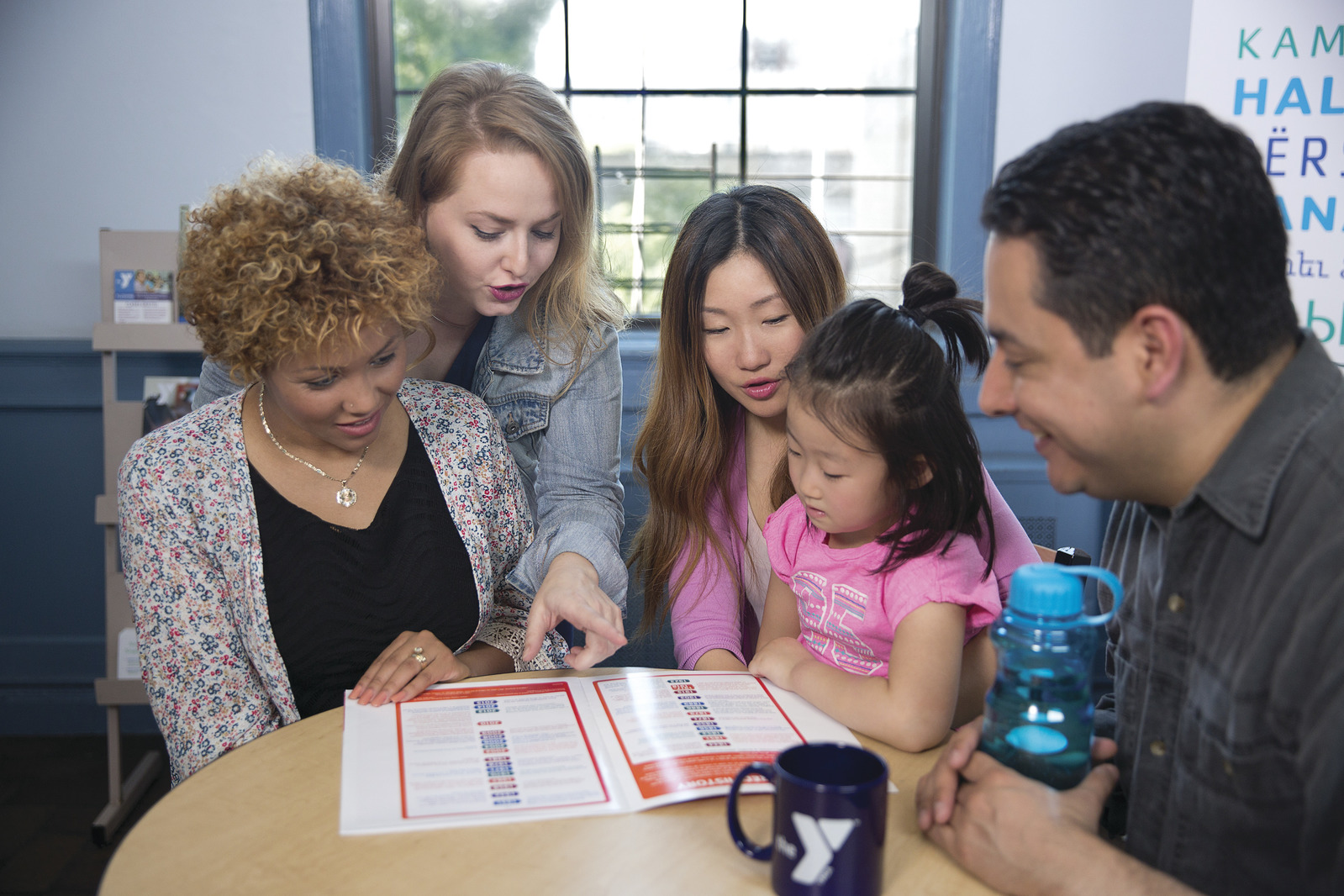 Four adults with a young girl in a group looking at a brochure.