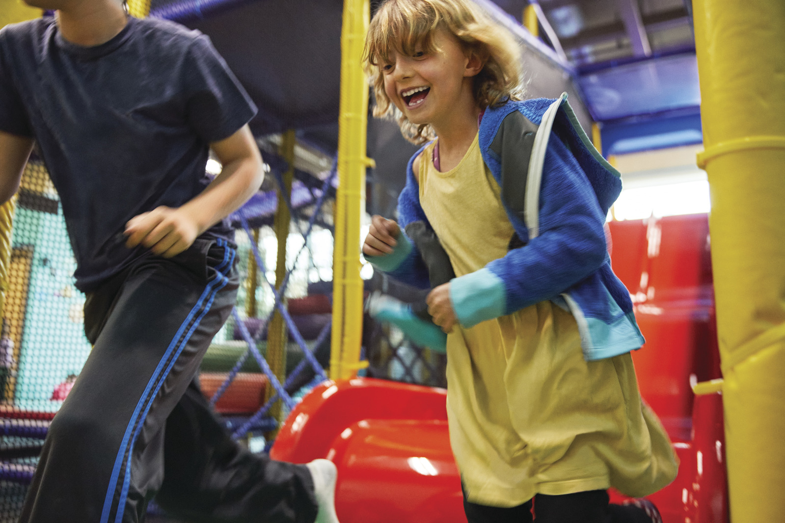 Young children running in play area with slides.