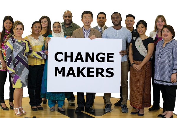 Group of people smiling a holding a sign that says "Change Makers."