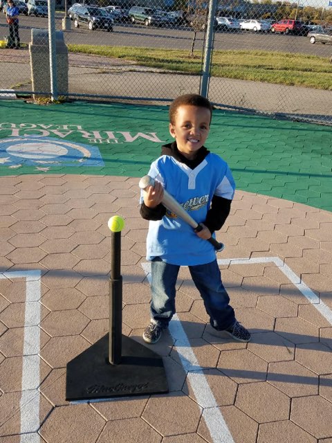 Young boy smiling while playing baseball.
