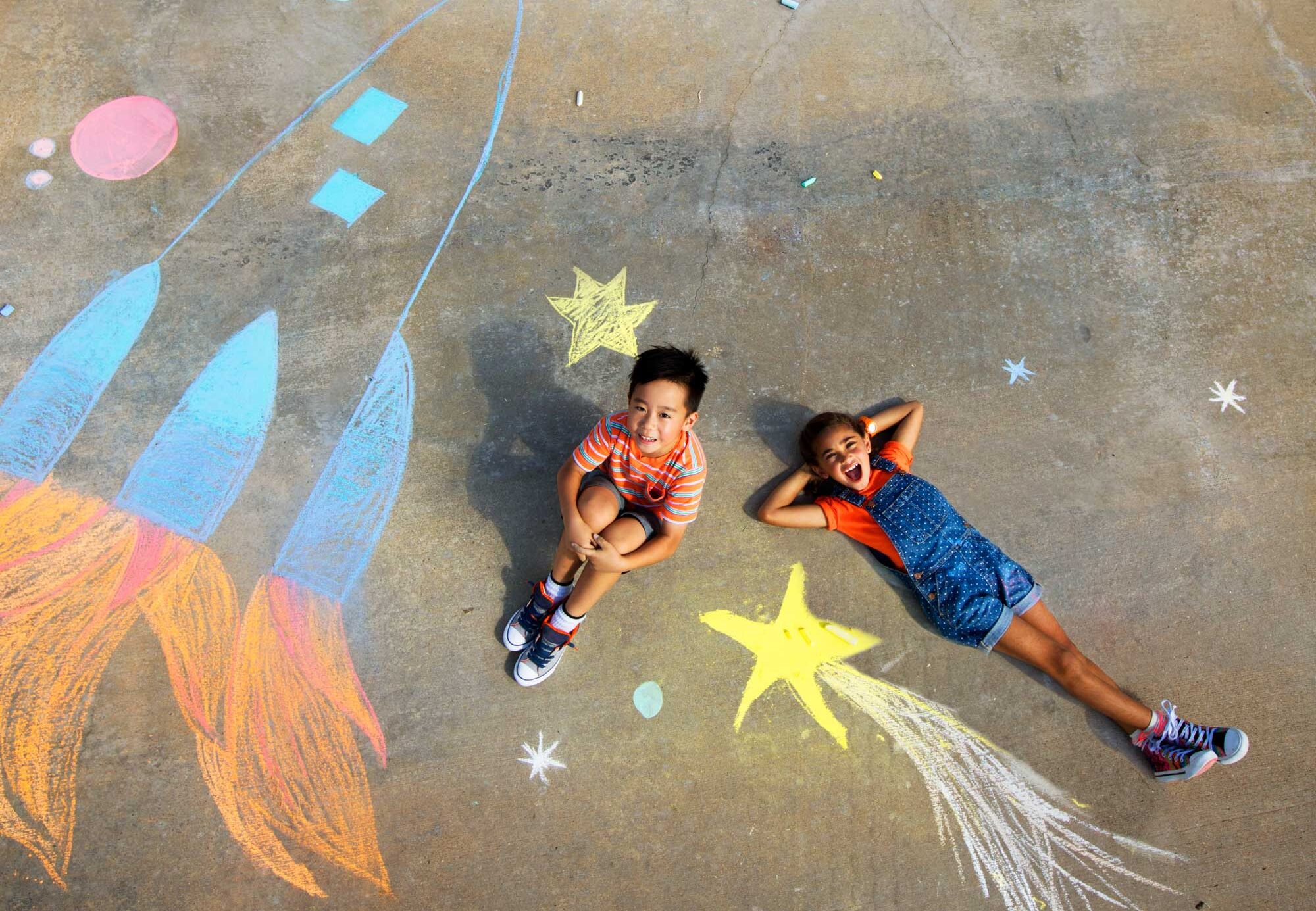 Young boy and girl coloring with chalk.