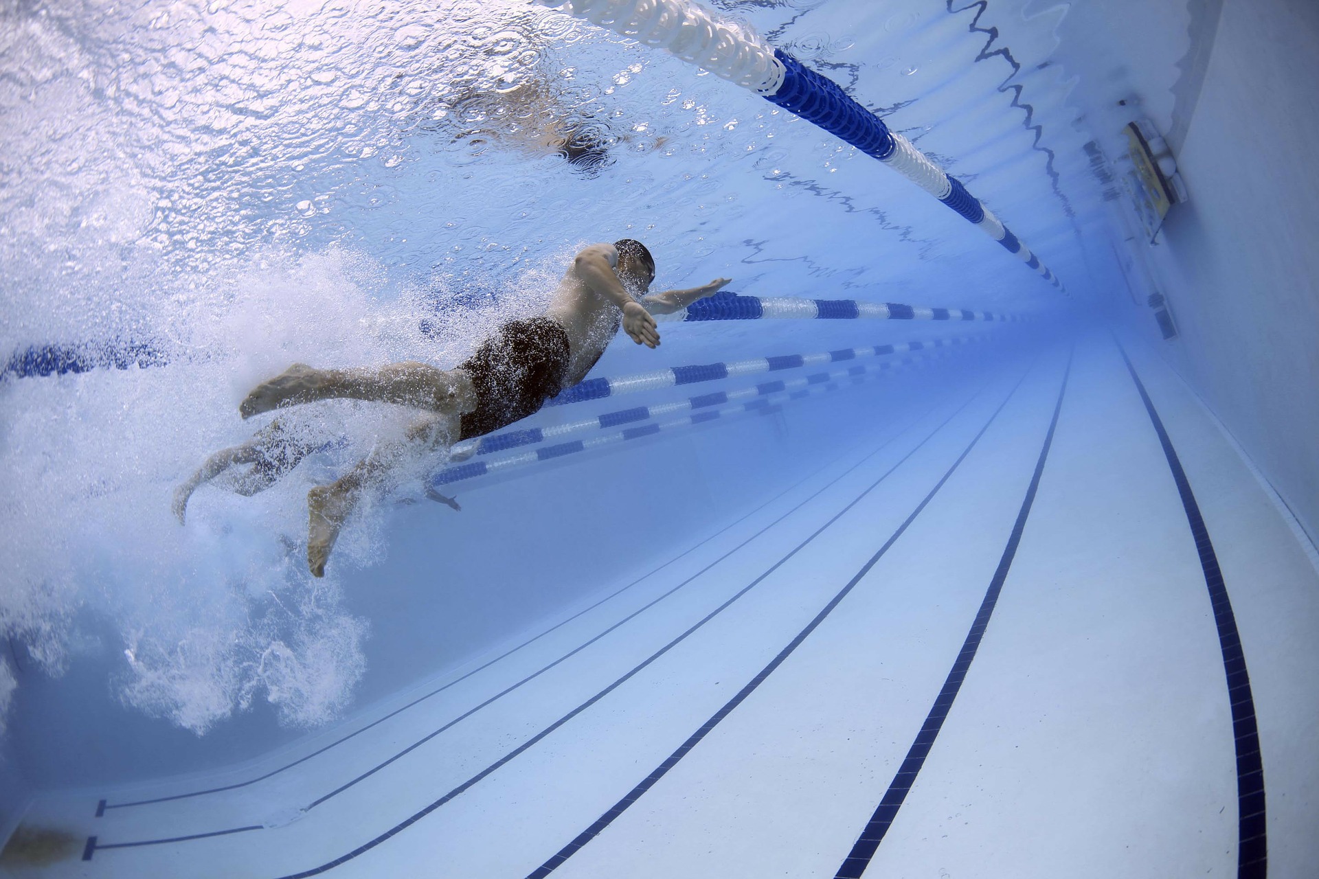 Man swimming underwater in a YMCA pool.
