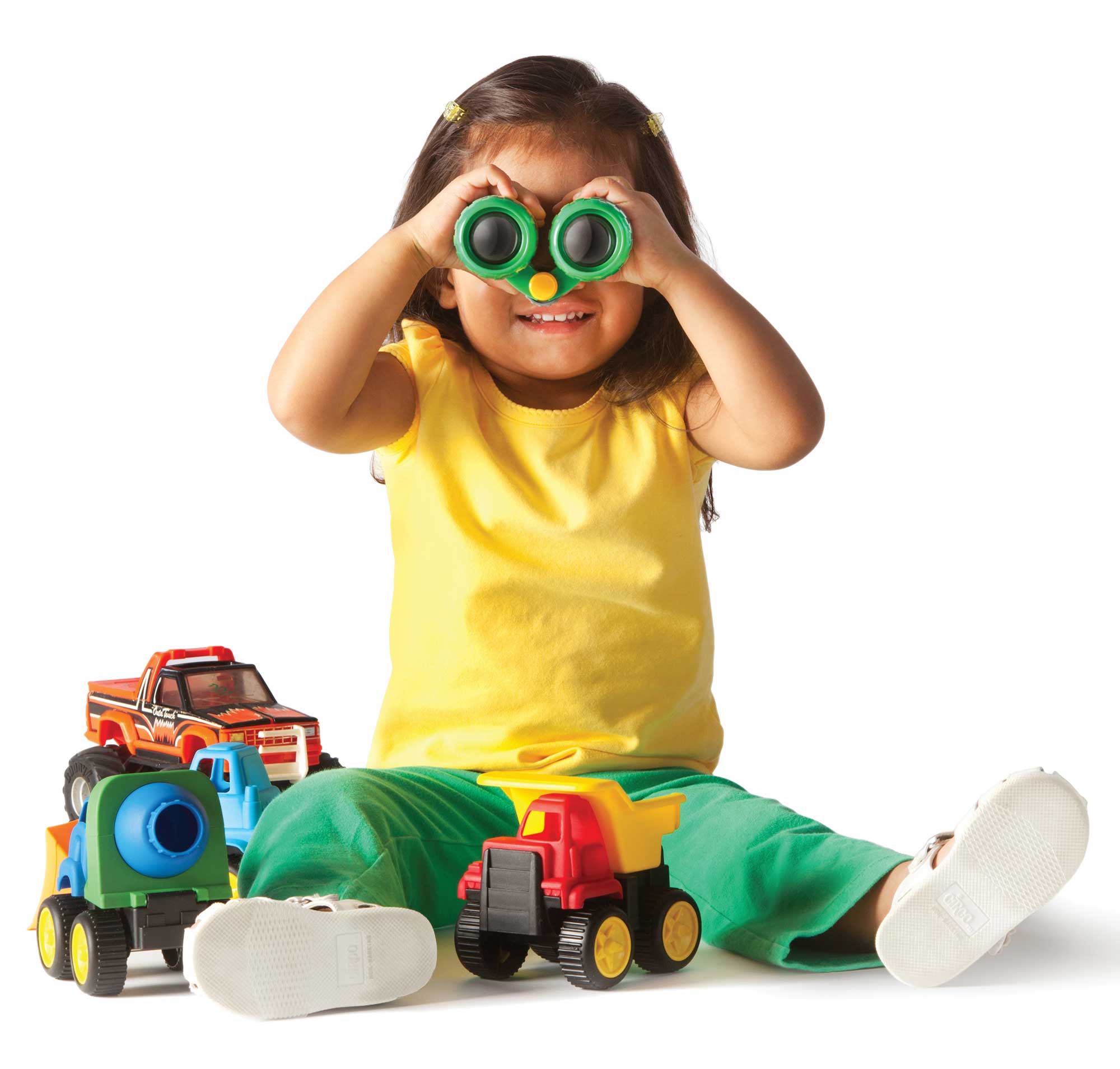 Young girl playing with trucks and holding binoculars.