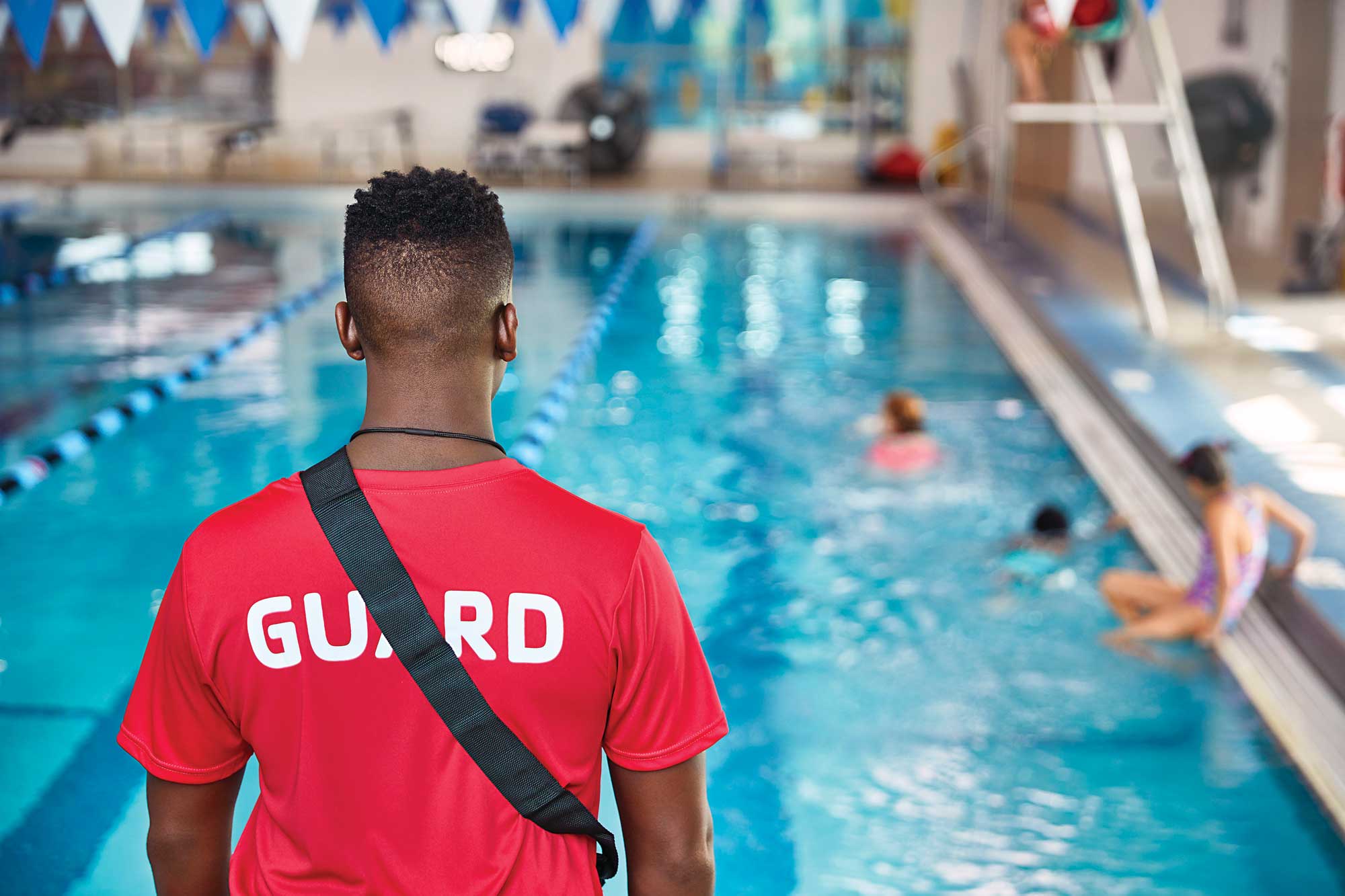 Lifeguard standing and facing the YMCA pool