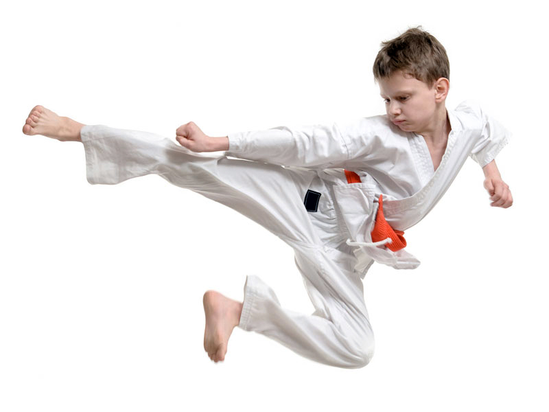 Young boy kick jumping in a YMCA martial arts class.