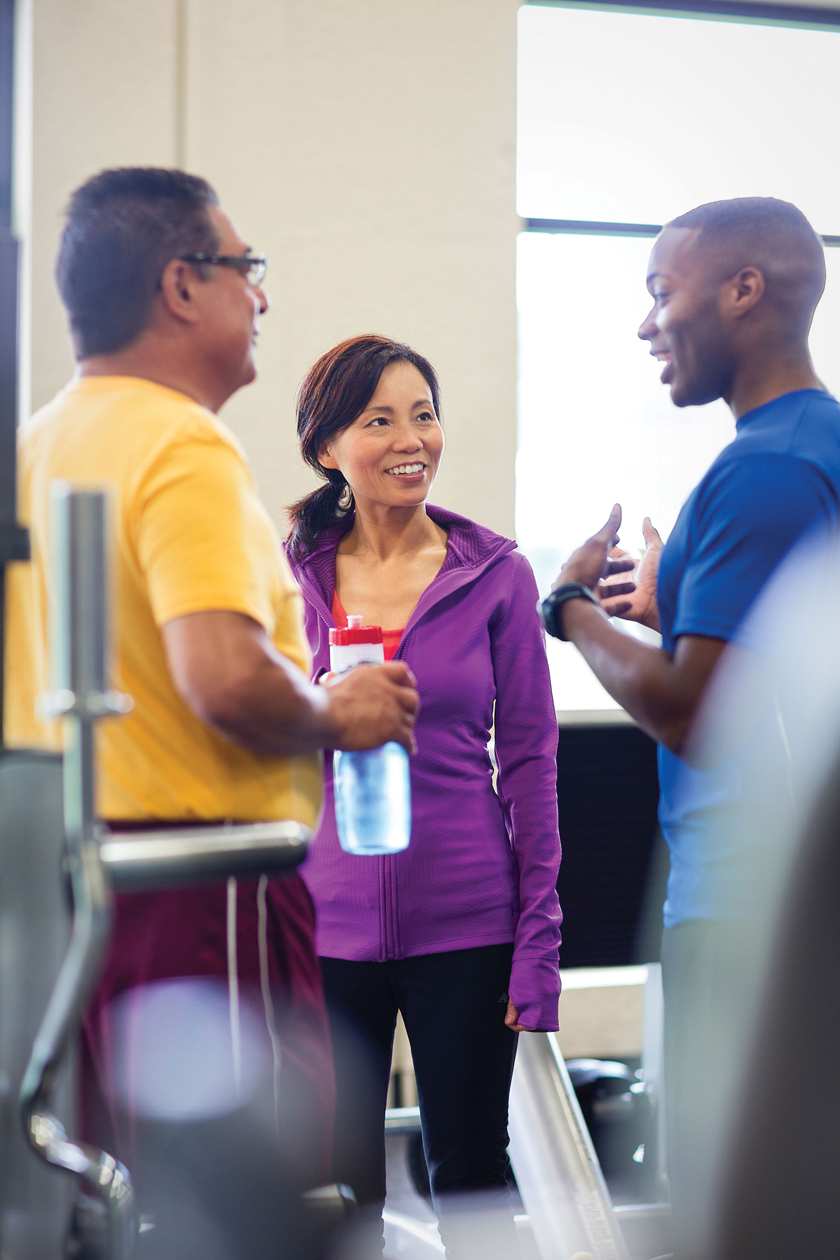 Two men and a woman having a nice chat at the YMCA gym.