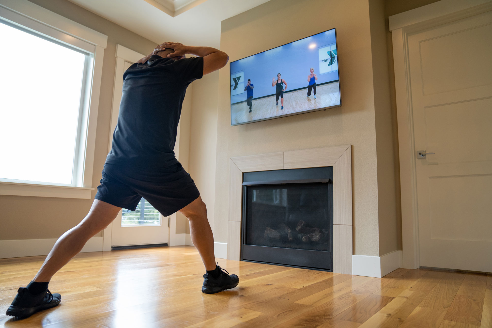 Man with a virtual YMCA membership using his tv to work out in his living room.