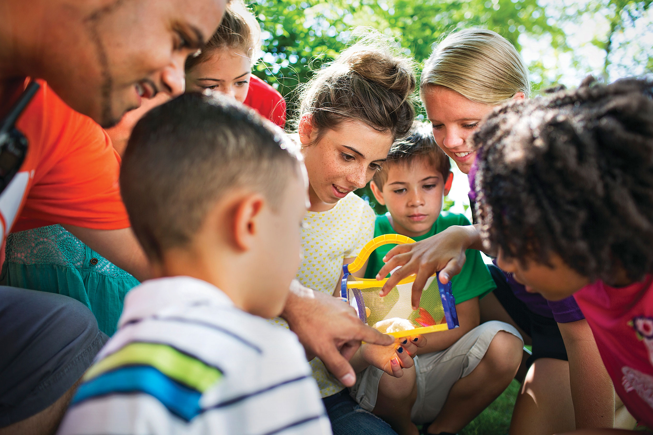 Kids checking out a bug catcher with camp counselor.