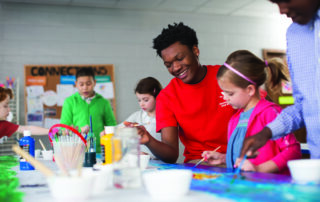 Teacher helping kids with a painting project.