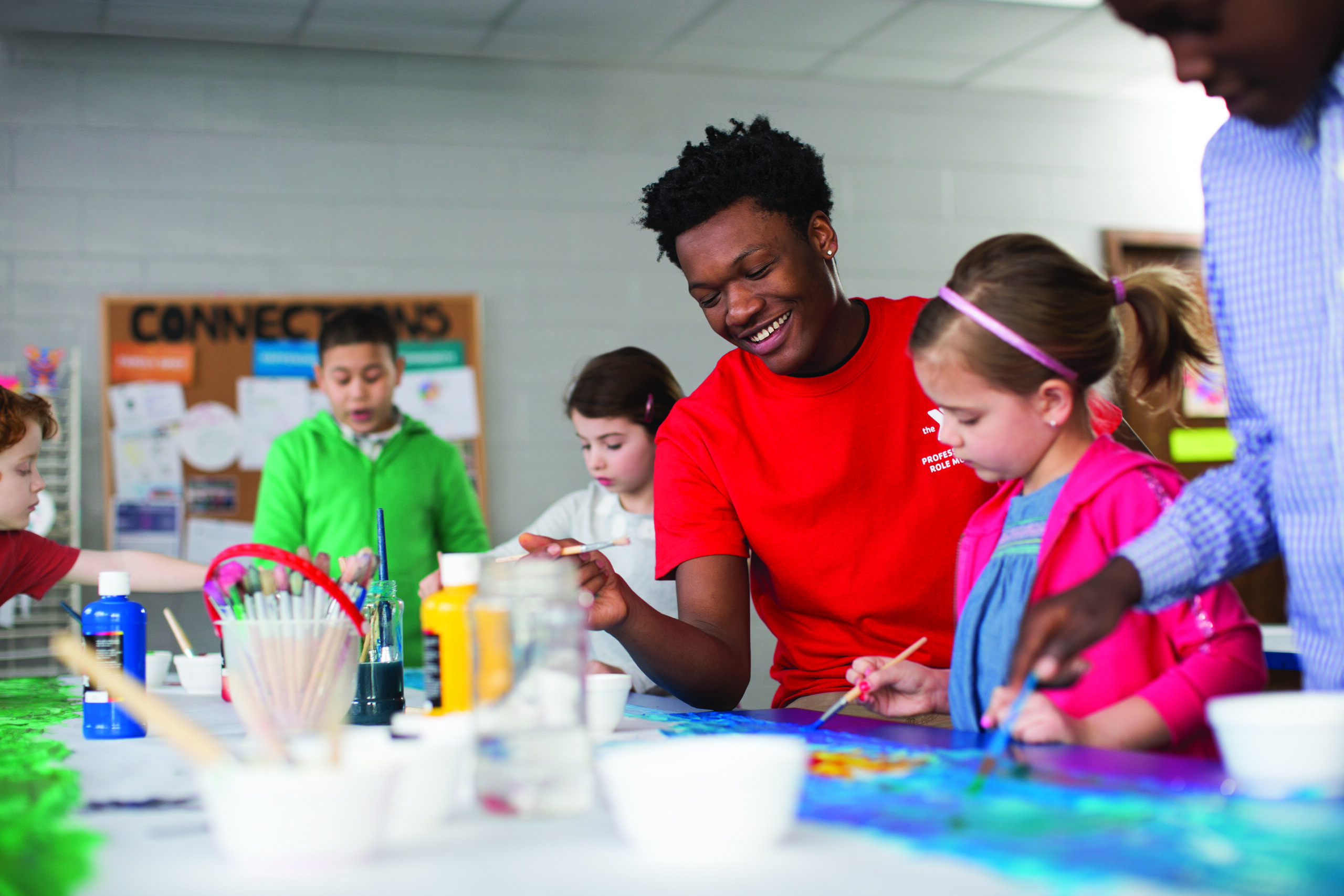 Teacher helping kids with a painting project.