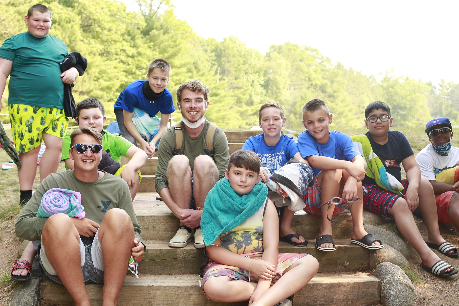 A group of young boys and guys smiling sitting one steps at YMCA Camp Jorn.