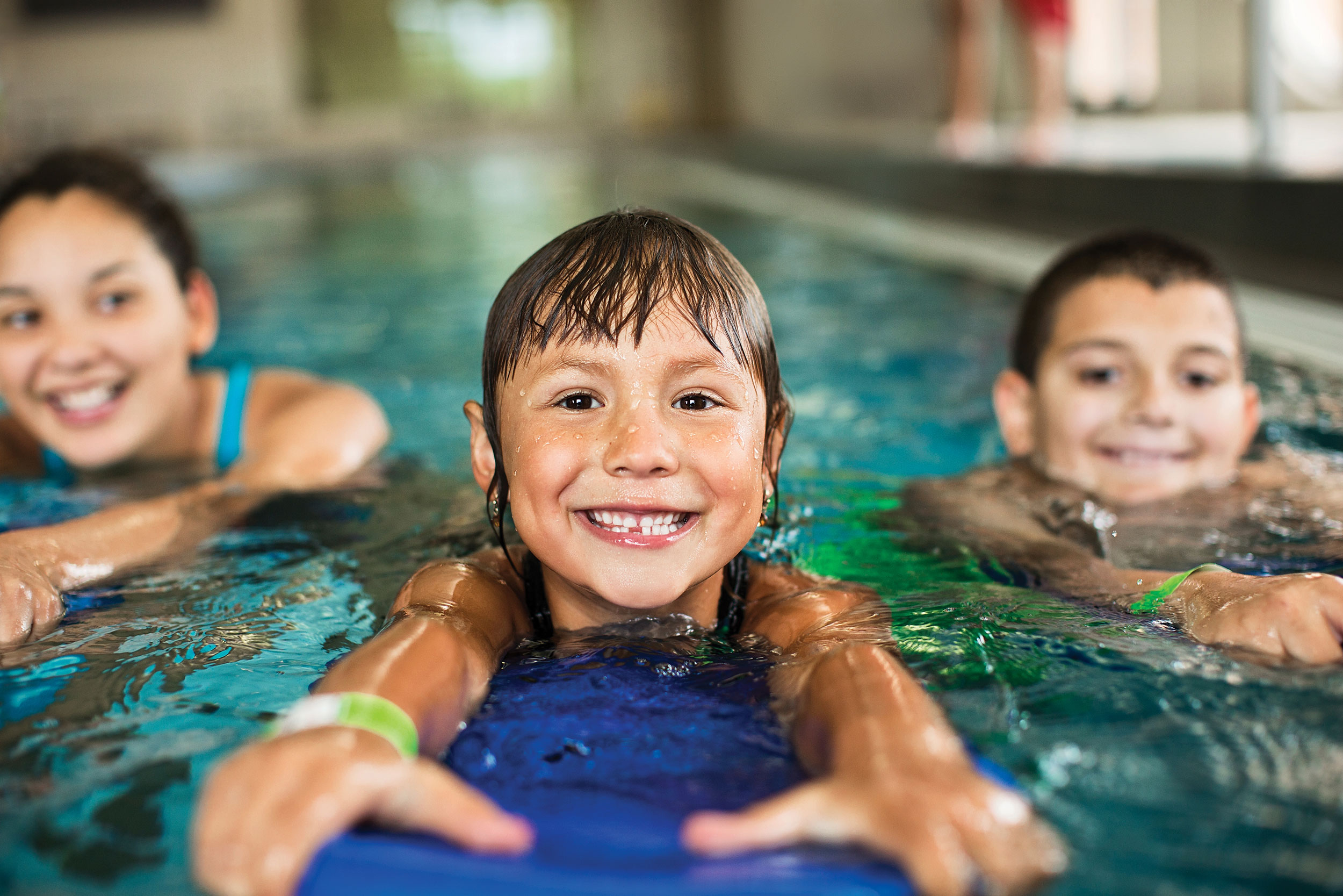 Three smiling children swimming at the YMCA pool at the Annual Luncheon.