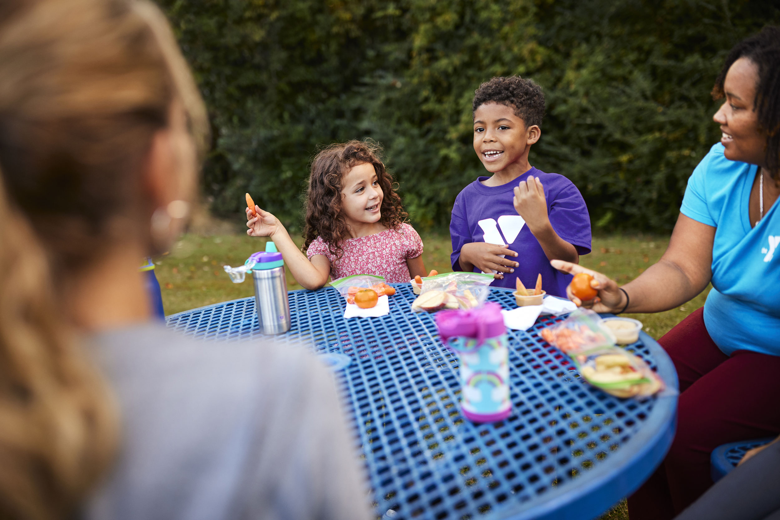 Kids enjoying a snack outside at YMCA camp.