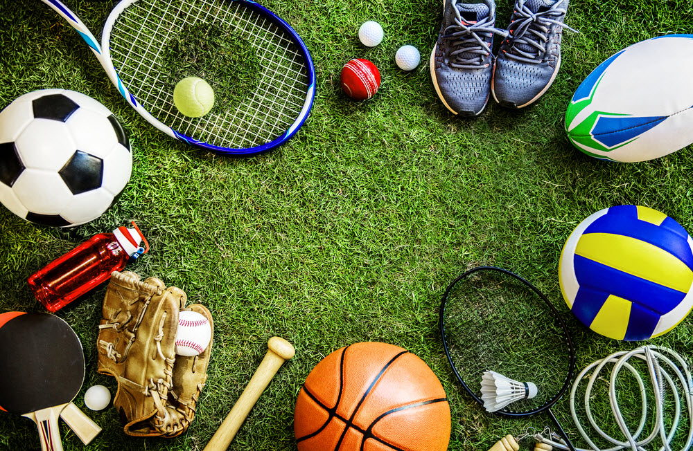 a basketball, volleyball, racketball, football, tennis shoes, golf balls, tennis racket, baseball glove bat and ball, ping pong paddles, and a soccer ball in grass