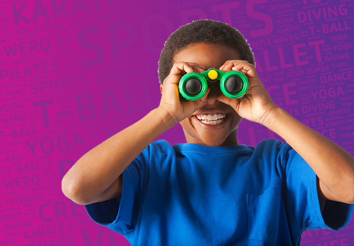 child smiling while holding up green binoculars to his eyes