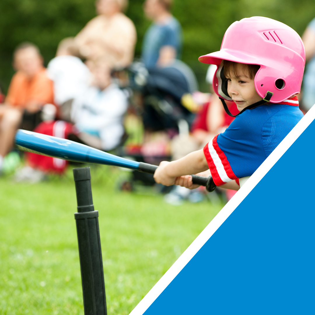 Young girl swinging a blue bat in t-ball wearing a pink helmet.