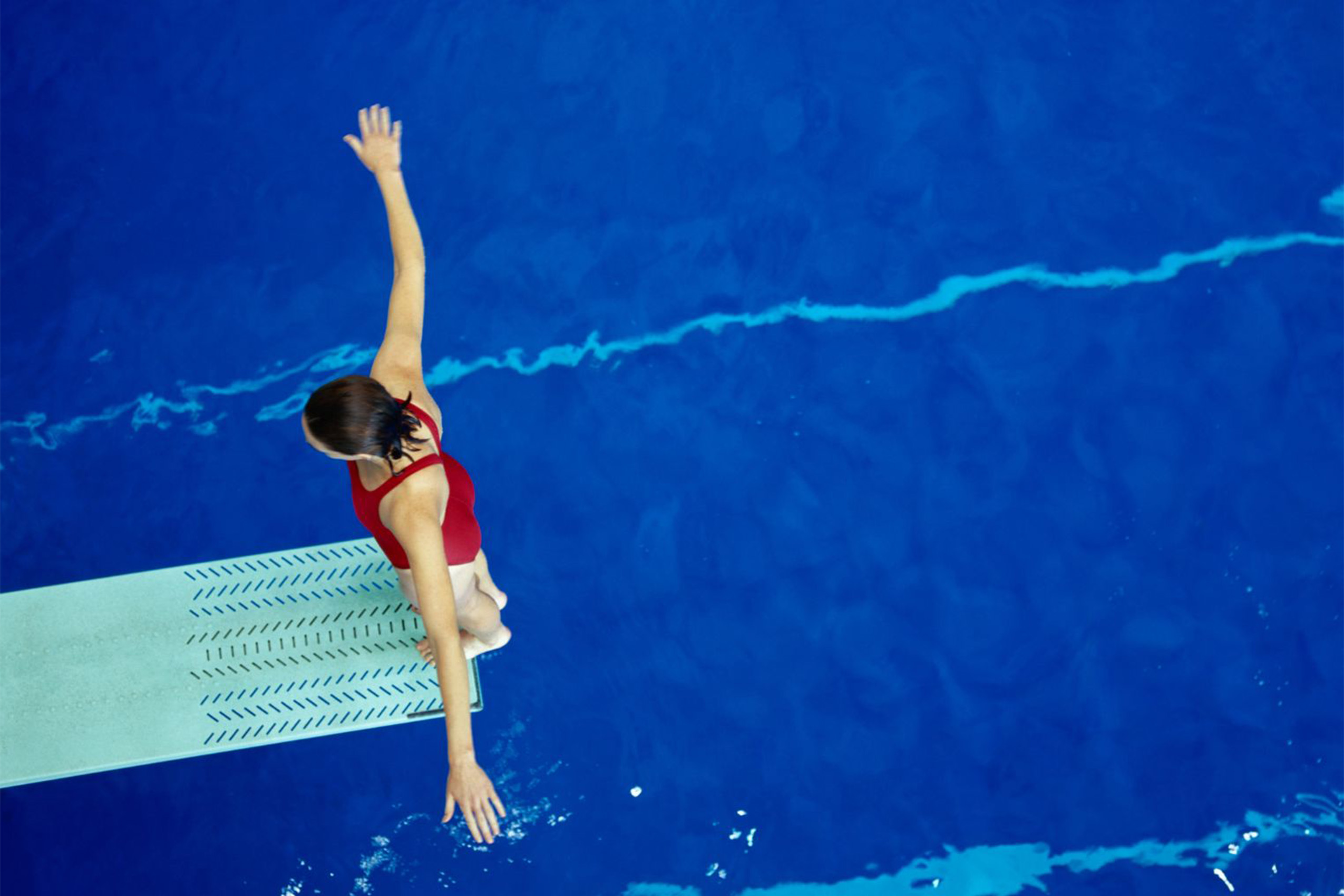 Women diving off a diving board into the YMCA pool.