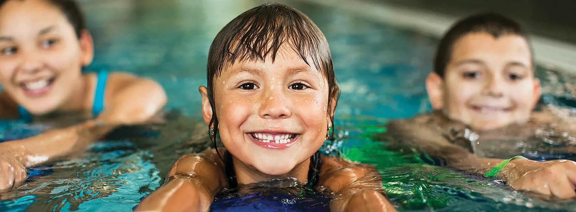 Three Smiling Children Swimming At The Ymca Pool At The Annual Luncheon.